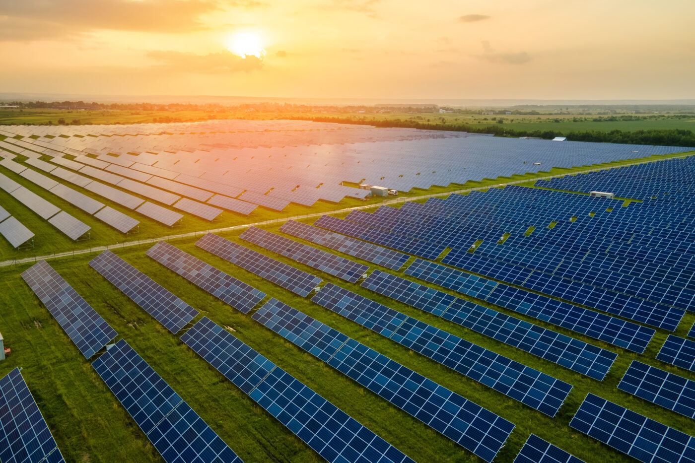 Aerial view of large sustainable electrical power plant with many rows of solar photovoltaic panels for producing clean electric energy in evening. Renewable electricity with zero emission concept.